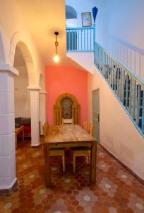 a dining room with a table and a staircase at Hotel Al Arboussas in Essaouira