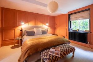a bedroom with a bed with orange walls and a window at Pond House in Lymington
