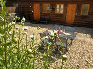 a patio with a table and chairs in front of a cabin at Seven Stars- hot tub & garden with fabulous views. in Llandrindod Wells