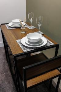 a wooden table with two plates and wine glasses at City Centre Studio 3 with Kitchenette, Free Wifi and Smart TV with Netflix by Yoko Property in Middlesbrough