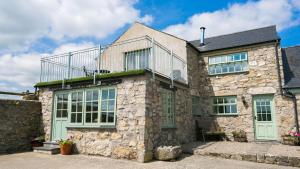 a stone house with a balcony on top of it at Ty Gwair in Pentraeth