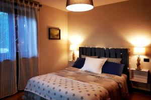 1 dormitorio con 1 cama con 2 lámparas y una ventana en La maison de Carmen, en Aosta