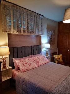 sypialnia z łóżkiem z różową pościelą i oknem w obiekcie La maison de Carmen w Aoście