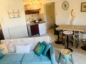 a living room with a blue couch and a kitchen at Le camélia in Tallard