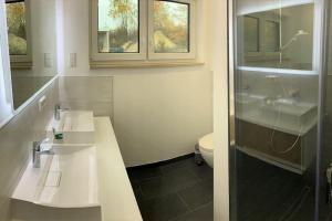 a bathroom with two sinks and a shower and a toilet at Casa Ida am Hainer See in Neukieritzsch