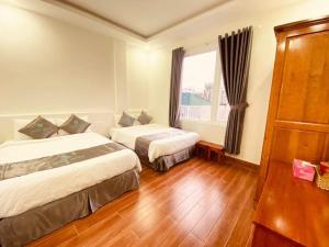 a hotel room with two beds and a window at Cara Hostel & Spa in Da Lat