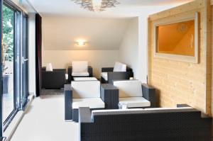 una sala de espera con sillas blancas y una ventana en Hotel Schepers, en Gronau