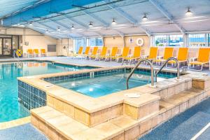 a large swimming pool with orange chairs in a building at Fenwick Inn in Ocean City