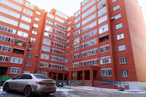 a car parked in front of a large brick building at Байзакова 133, новостройка in Pavlodar