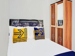uma cama com almofadas amarelas e azuis em SPOT ON 1711 Serayu Sumbersari Residence em Malang