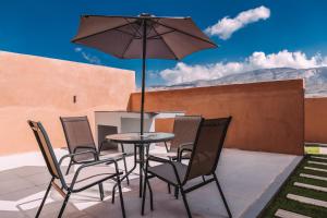 een tafel met stoelen en een parasol op een patio bij MountSun Stay Jabal Shams in Sa‘ab Banī Khamīs