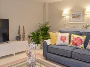 a living room with a blue couch and a tv at Whitehouse Studio in Roslin