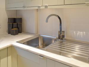 uma cozinha com um lavatório de aço inoxidável com uma torneira em Whitehouse Studio em Roslin