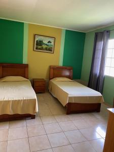 duas camas num quarto com paredes verdes e amarelas em Canal Inn B&B Panama na Cidade do Panamá