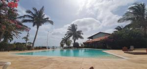 a swimming pool with palm trees and a house at Halcyon Residence in Santa Maria