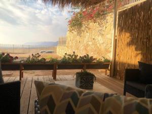 a patio with a stone wall and a table with a plant at Beautiful Dead Sea Unit in Ovnat