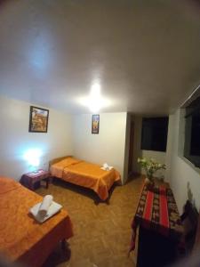 a hotel room with two beds and a table at Secret Valley House Cusco in Ollantaytambo