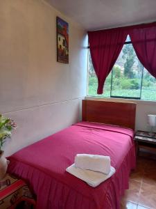a bedroom with a pink bed with a window at Secret Valley House Cusco in Ollantaytambo