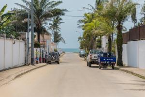 Une rue vide avec des palmiers et l'océan dans l'établissement Ravissant appartement 2ch à la plage, à Pointe-Noire