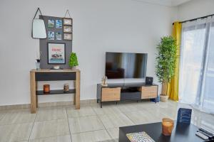 ein Wohnzimmer mit einem Flachbild-TV und einem Tisch in der Unterkunft Ravissant appartement 2ch à la plage in Pointe-Noire