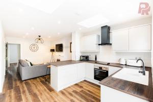Birmingham 4 Bedroom Home - Driveway & Garden - Brand New! في برمنغهام: مطبخ وغرفة معيشة مع دواليب بيضاء وأريكة