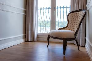 uma cadeira sentada em frente a uma janela em Castelo Boutique Hotel em Fraiburgo