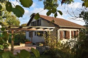 a white house with a wooden pergola at Maison à la campagne entre Nancy et Pont-à-Mousson in Malleloy
