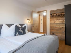 - une chambre avec un lit blanc et un mur en bois dans l'établissement Ferienwohnung Tirolglück mit großem Garten, à St. Johann in Tirol