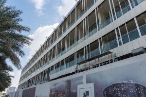 a large building with a palm tree in front of it at Al Raha lofts 1 in Al Qurayyah