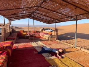 Eine Frau, die in der Wüste liegt. in der Unterkunft Erg Chegaga Camp & Activites in M’hamid El Ghizlane
