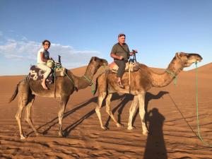 two people riding on camels in the desert at Erg Chegaga Camp & Activites in Mhamid