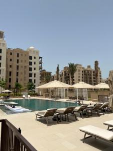 uma piscina com espreguiçadeiras e guarda-sóis em MJL Rahaal2- 301Apartament no Dubai