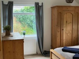 a bedroom with a bed and a window with curtains at Entire house near beaches, footpaths, dog friendly in Barnstaple