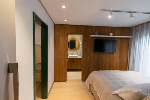 1 dormitorio con cama, lavabo y espejo en Apto Pátio Goods Br (café da manhã incluso), en Gramado