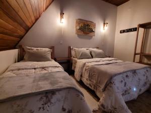 um quarto com duas camas num quarto em Villa das Palmeiras Chalés & Camping em São Bento do Sapucaí