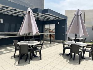 two tables and chairs with white umbrellas on a patio at Bonito depa san isidro cama queen home office wifi y cochera in Lima