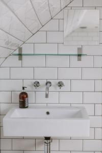 a white sink in a white tiled bathroom at Dunruadh Cottage in Gartocharn