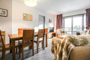 a living room with a table and a dining room at South-facing newly renovated 2-bed apartment Les Terrasses d'Eos in Flaine