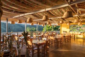 una sala da pranzo con tavoli, sedie e finestre di Pousada Piratas do Barro Branco a Pedregulho