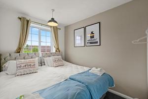 a bedroom with a large white bed with a window at Cosy Home with Large Driveway, Private Garden, Super-Fast Wifi and Smart TV - Perfect for Contractors, Groups, Relocation and Corporate Guests - by Yoko Property in Northampton