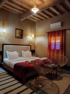 une chambre avec un lit, une table et des chaises dans l'établissement kasbah Dar Bahnini, à Skoura