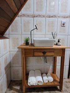 a bathroom with a sink and towels on a table at Villa das Palmeiras Chalés & Camping in São Bento do Sapucaí