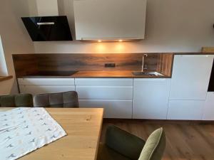 a kitchen with white cabinets and a sink and a table at Apart Smart in Bruck am Ziller