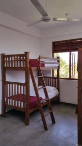 2 łóżka piętrowe w pokoju z wentylatorem sufitowym w obiekcie Hitchhike Backpackers w mieście Mount Lavinia