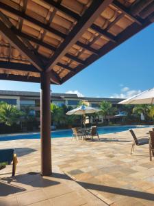 卡馬薩里的住宿－Apartamento em guarajuba 200m da praia，游泳池旁带椅子和遮阳伞的天井