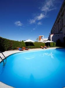 una gran piscina azul con sillas y sombrillas en Colón Tuy, en Tui