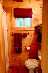 bagno in legno con servizi igienici e finestra. di Wild Fox Cabins a The Pines