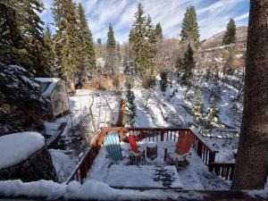 una terraza cubierta de nieve con 2 sillas y un árbol en Hideaway Above The Stream Sundance, Utah, en Sundance