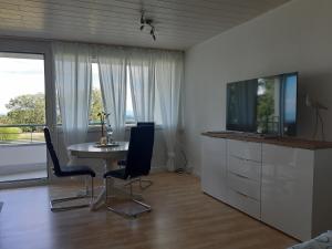ein Wohnzimmer mit einem Tisch, Stühlen und einem TV in der Unterkunft Ferienzentrum Bodensee in Oberteuringen