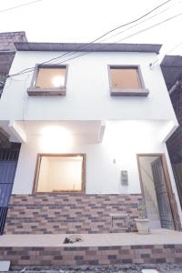 una casa bianca con tre finestre e una scala in mattoni di Apartamentos Prana a Itacaré